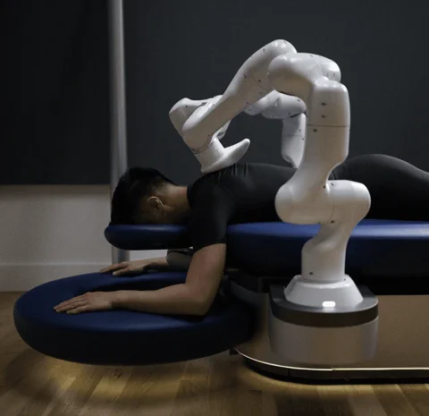 The Aescape robotic massage table with its two arms positioned over a person's back.