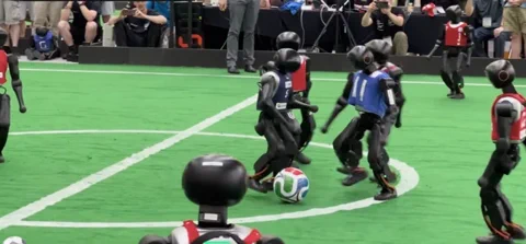 Two squads of humanoid robots battle it out on a football pitch during the historic 11-a-side debut at RoboCup 2026.